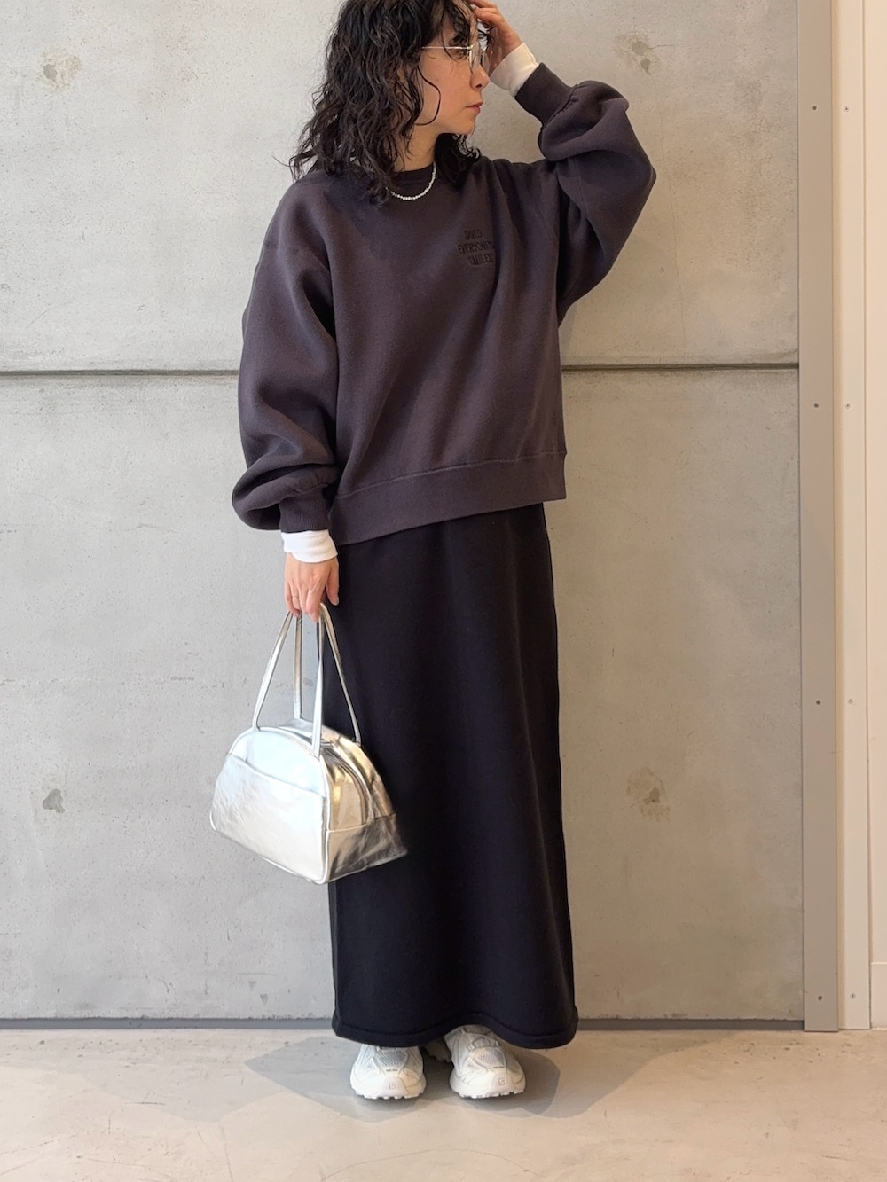 シルバー系のボストンバッグ、ブラック系のスカート、ホワイト系のスニーカーを着用したレディースの秋コーディネートの2枚目の写真