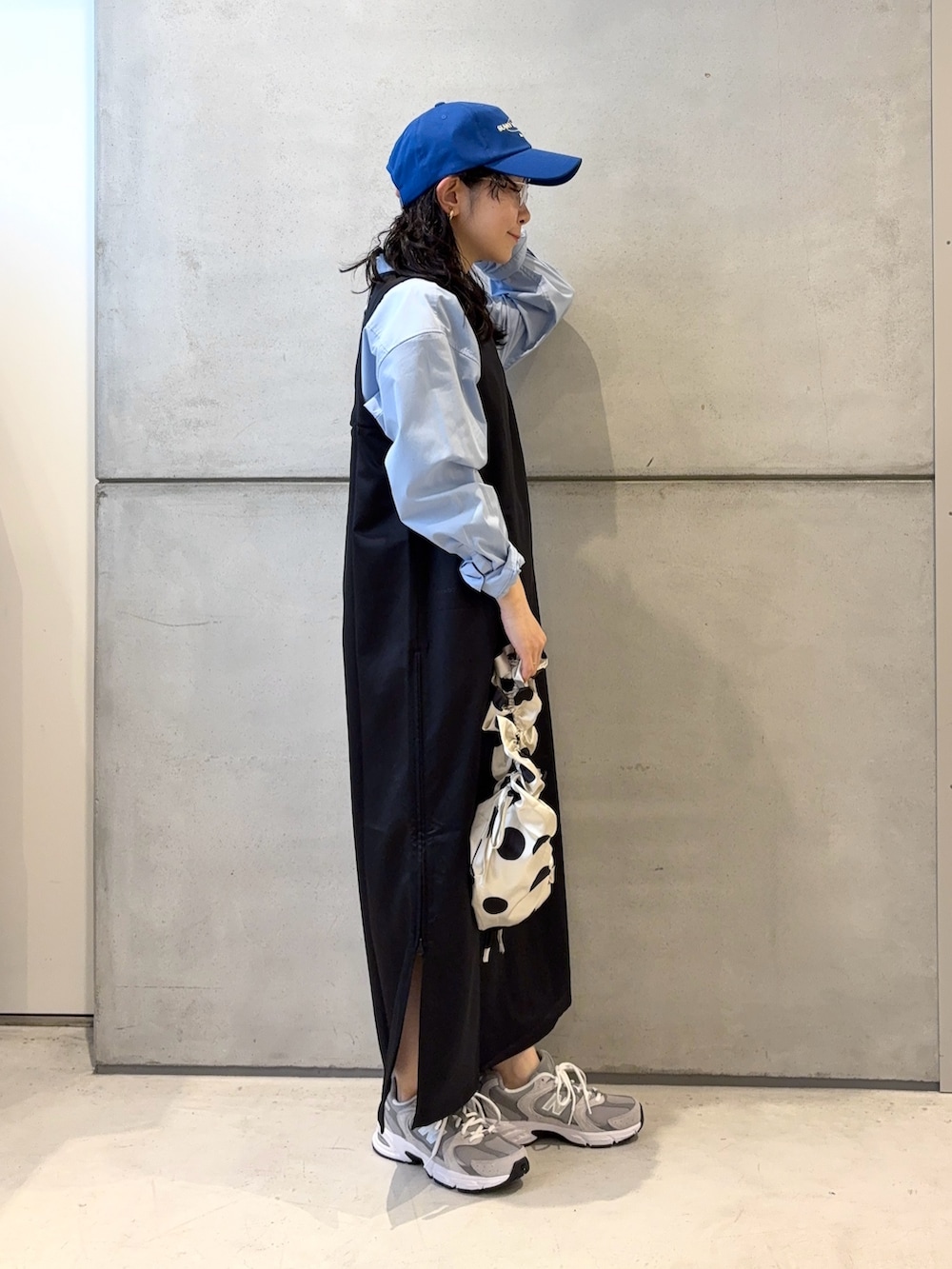 グレー系のスニーカー、ホワイト系のショルダーバッグ、ブラック系のワンピースを着用したレディースの春コーディネートの3枚目の写真