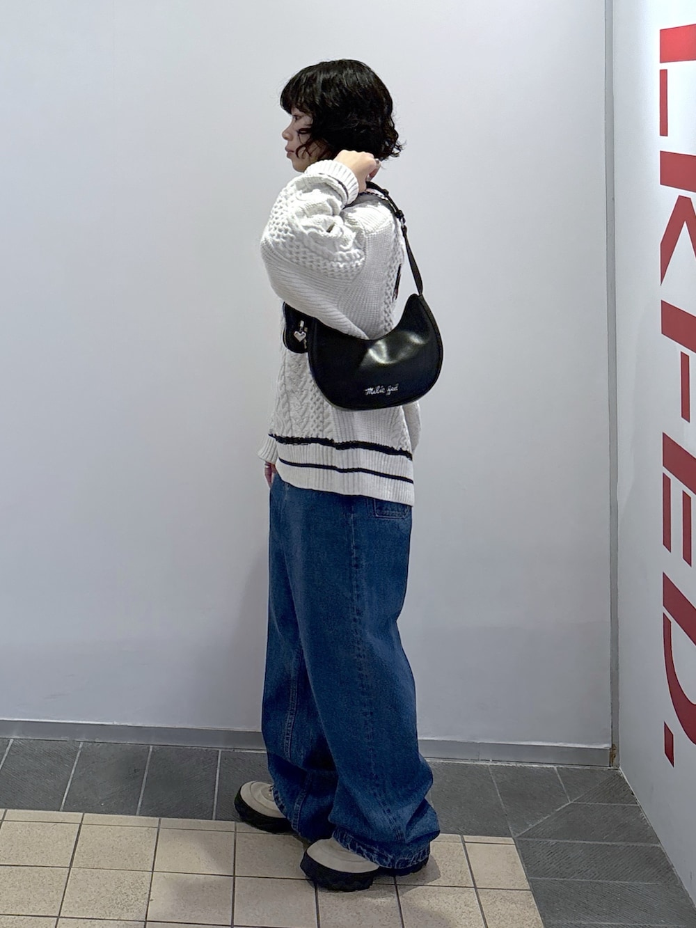 ブルー系のデニムパンツ、ホワイト系のニット/セーター、ブラック系のハンドバッグを着用したレディースの秋コーディネートの3枚目の写真