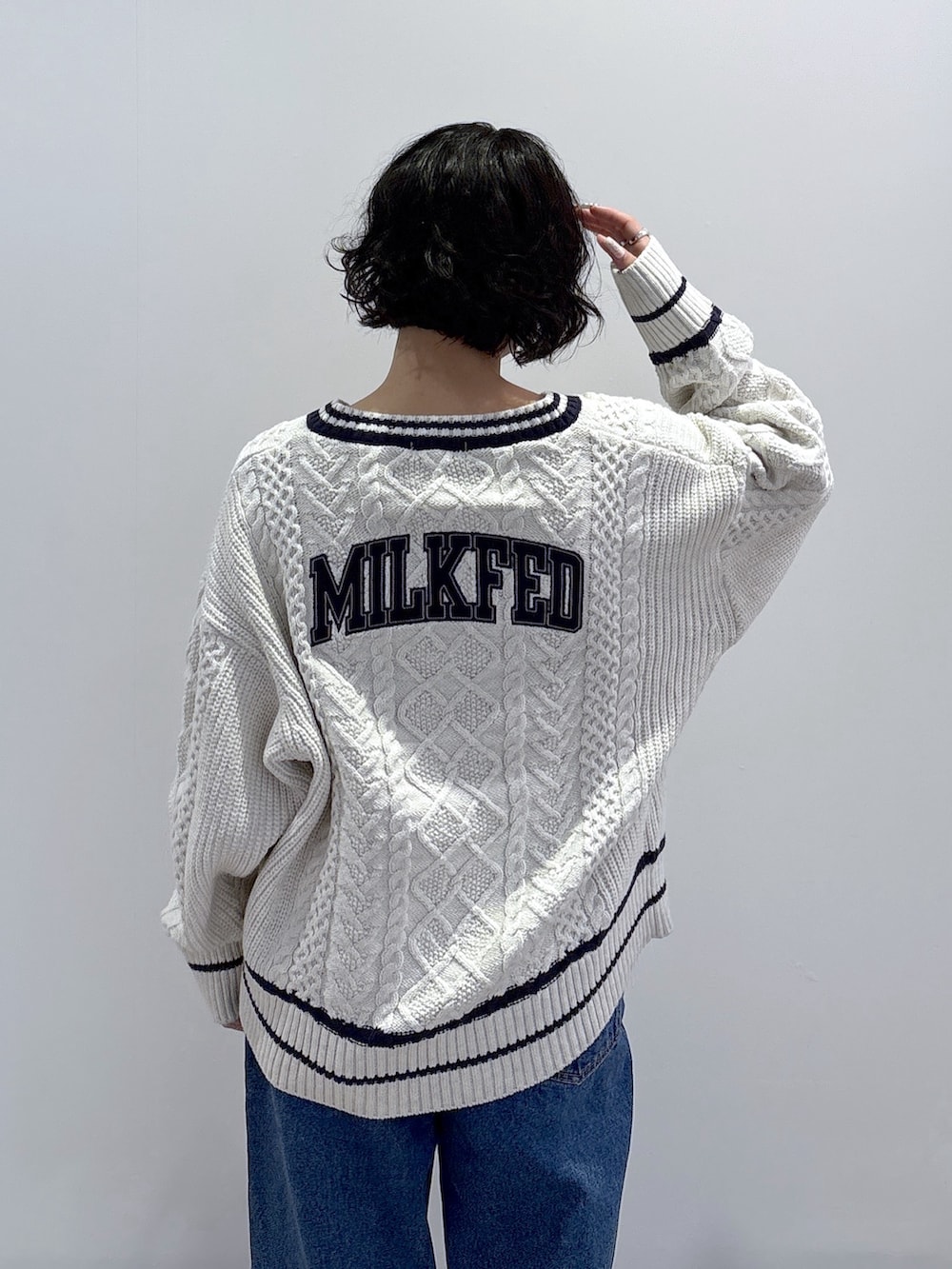 ブルー系のデニムパンツ、ホワイト系のニット/セーター、ブラック系のハンドバッグを着用したレディースの秋コーディネートの8枚目の写真