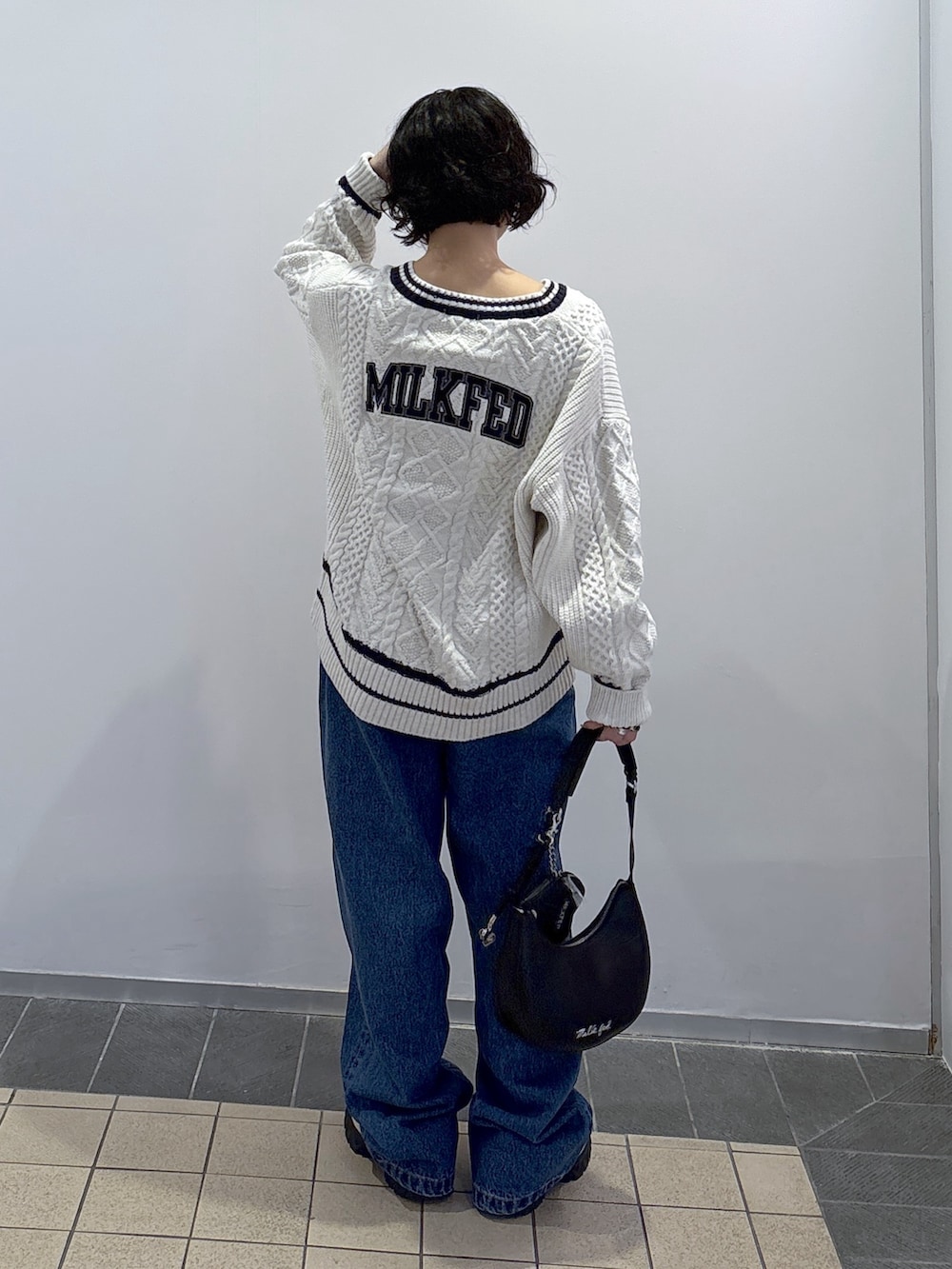 ブルー系のデニムパンツ、ホワイト系のニット/セーター、ブラック系のハンドバッグを着用したレディースの秋コーディネートの4枚目の写真