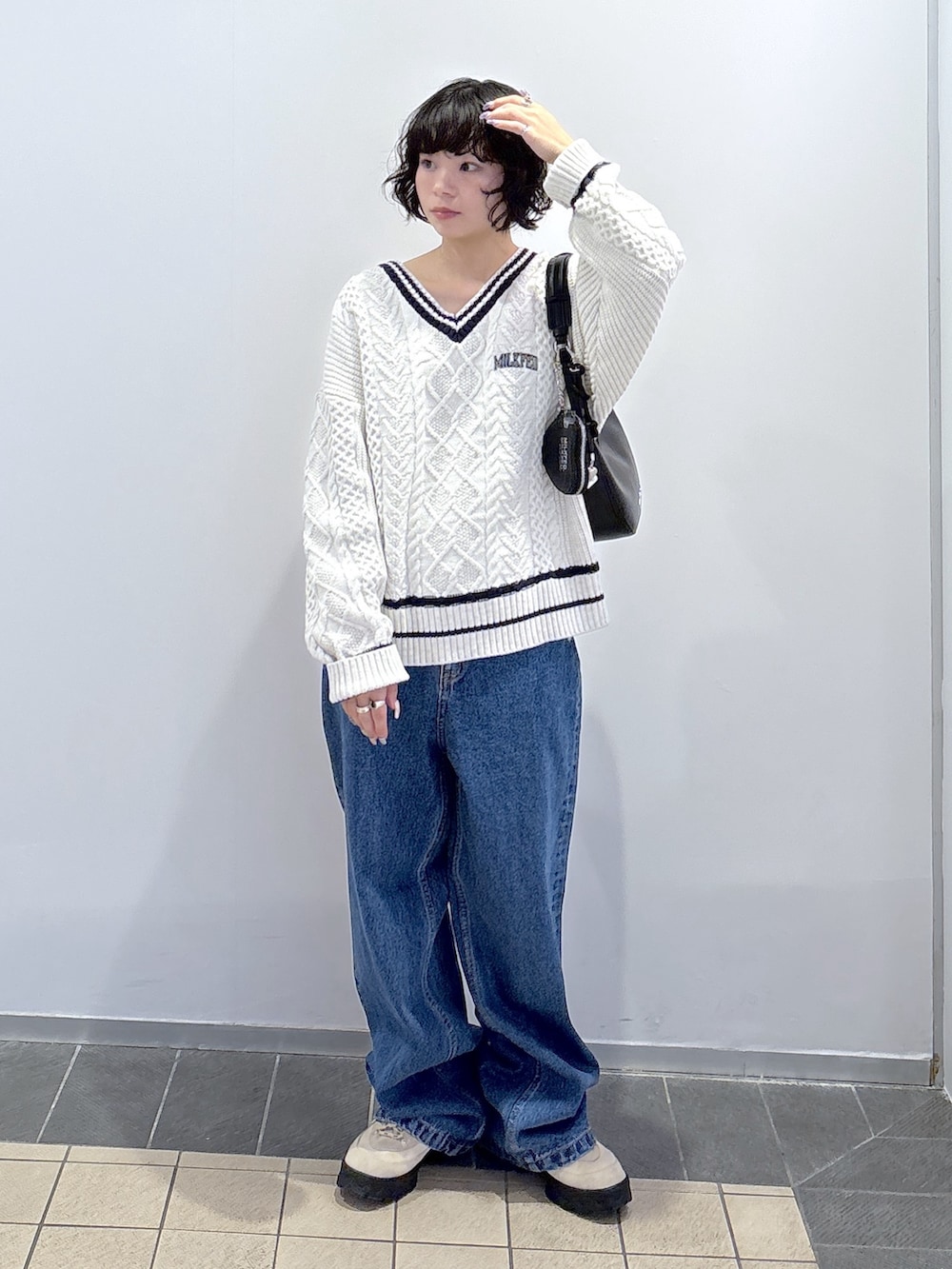 ブルー系のデニムパンツ、ホワイト系のニット/セーター、ブラック系のハンドバッグを着用したレディースの秋コーディネートの2枚目の写真