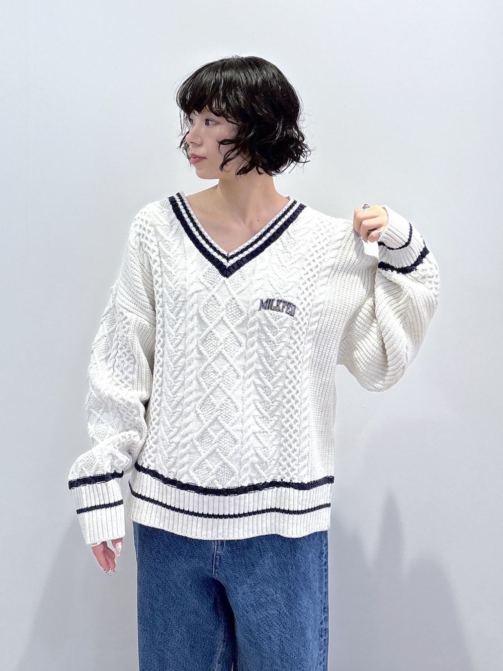 ブルー系のデニムパンツ、ホワイト系のニット/セーター、ブラック系のハンドバッグを着用したレディースの秋コーディネートの7枚目の写真
