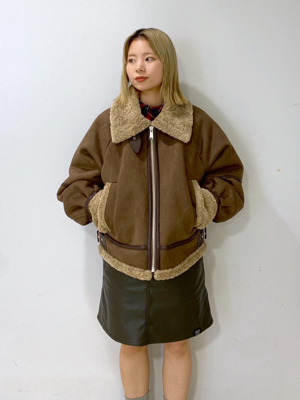 ブラウン系のムートンコート、シルバー系のショルダーバッグ、グリーン系のジャンパースカートを着用したレディースの冬コーディネートの8枚目の写真