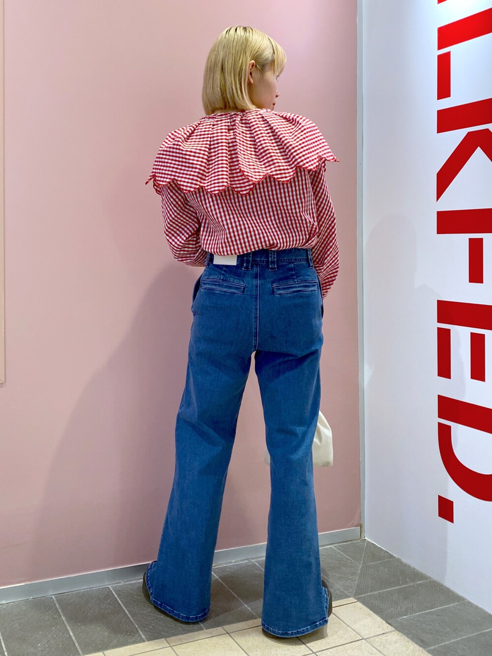 レッド系のシャツ/ブラウス、ブルー系のデニムパンツ、ホワイト系のハンドバッグを着用したレディースの春コーディネートの2枚目の写真