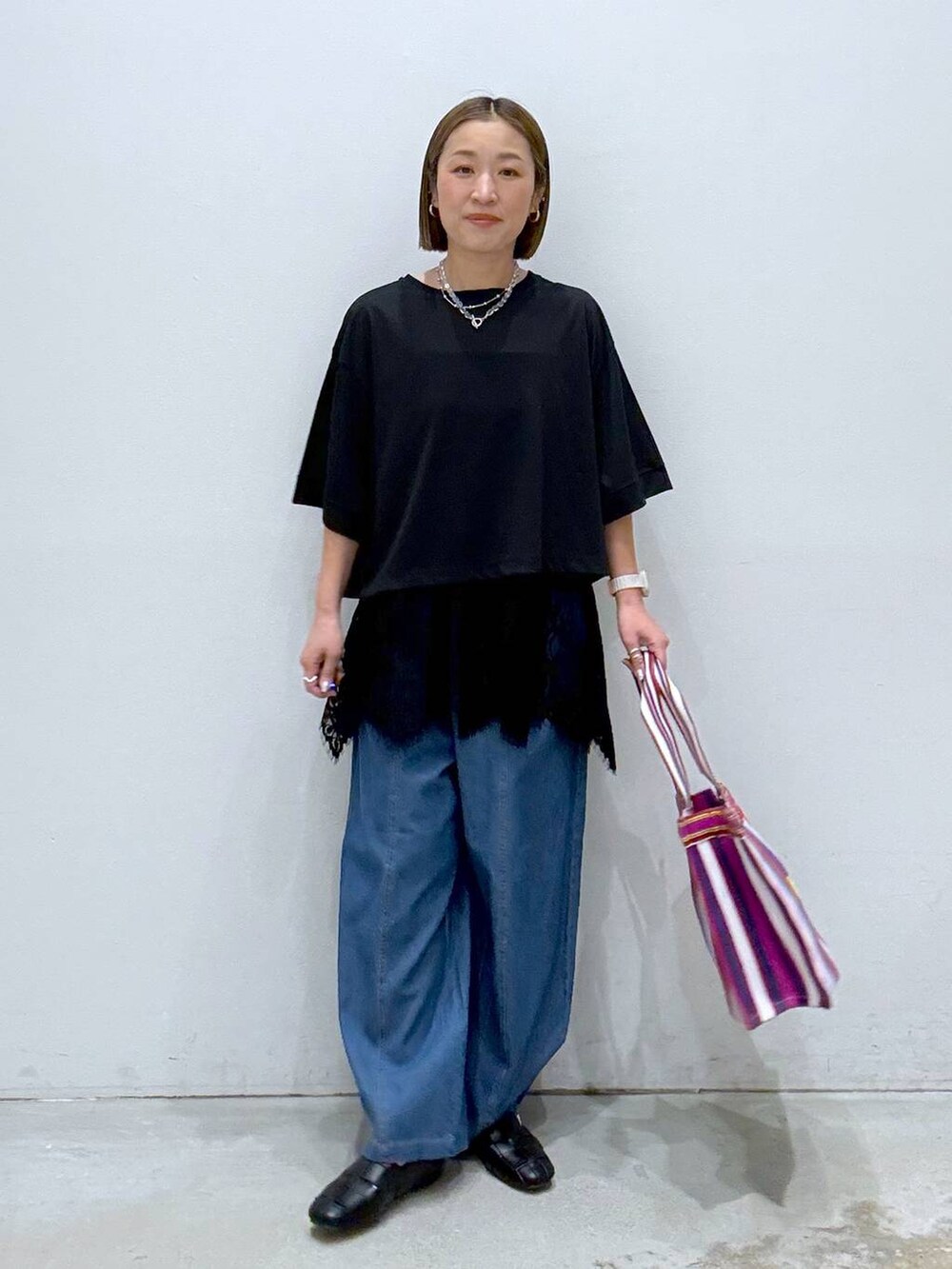 ブラック系のTシャツ/カットソー、ブラック系のパンプス、ブルー系のデニムパンツを着用したレディースの春コーディネートの2枚目の写真