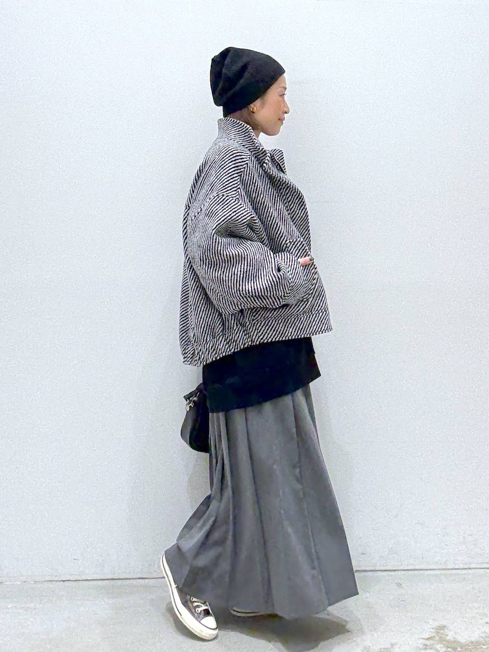 グレー系のスカート、ブラウン系のスニーカー、ブラック系のボストンバッグを着用したレディースの秋コーディネートの5枚目の写真