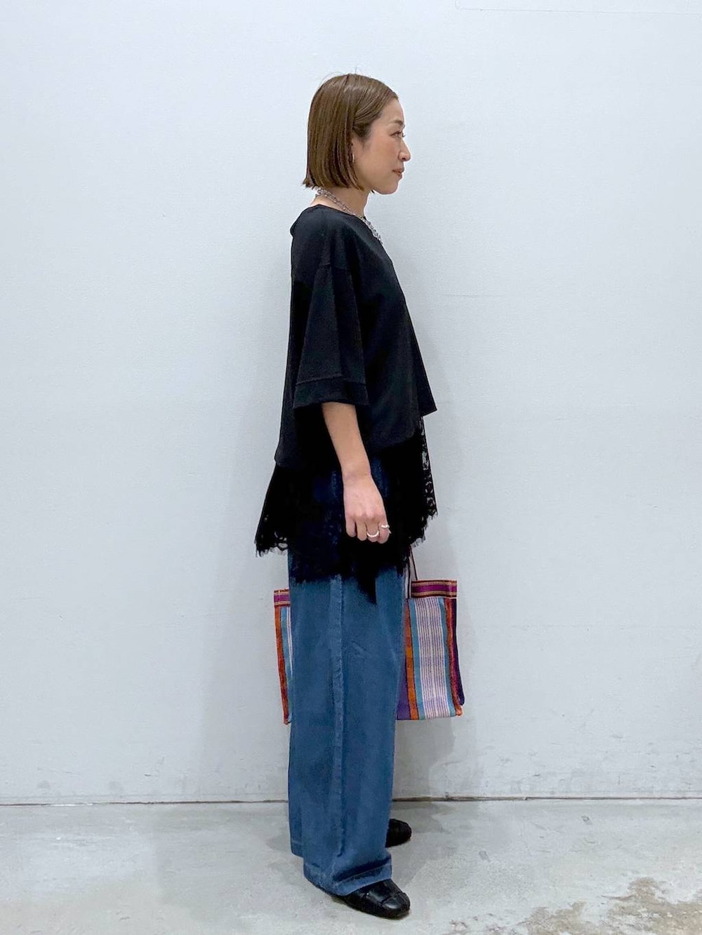 ブラック系のTシャツ/カットソー、ブラック系のパンプス、ブルー系のデニムパンツを着用したレディースの春コーディネートの5枚目の写真