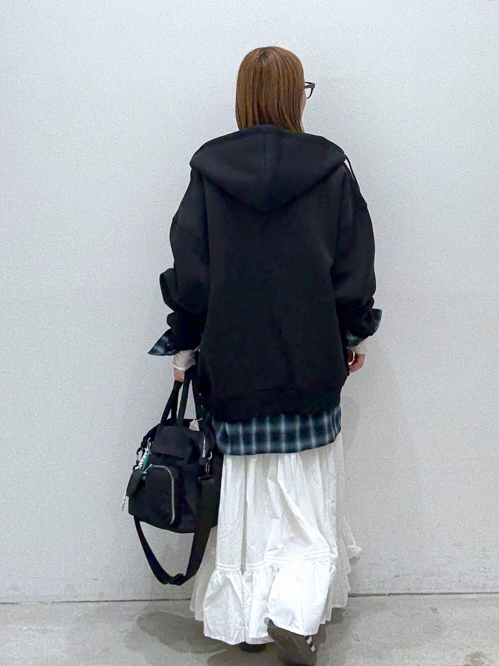 ブラック系のパーカー、ホワイト系のTシャツ/カットソー、ブラック系のトートバッグを着用したレディースの冬コーディネートの4枚目の写真