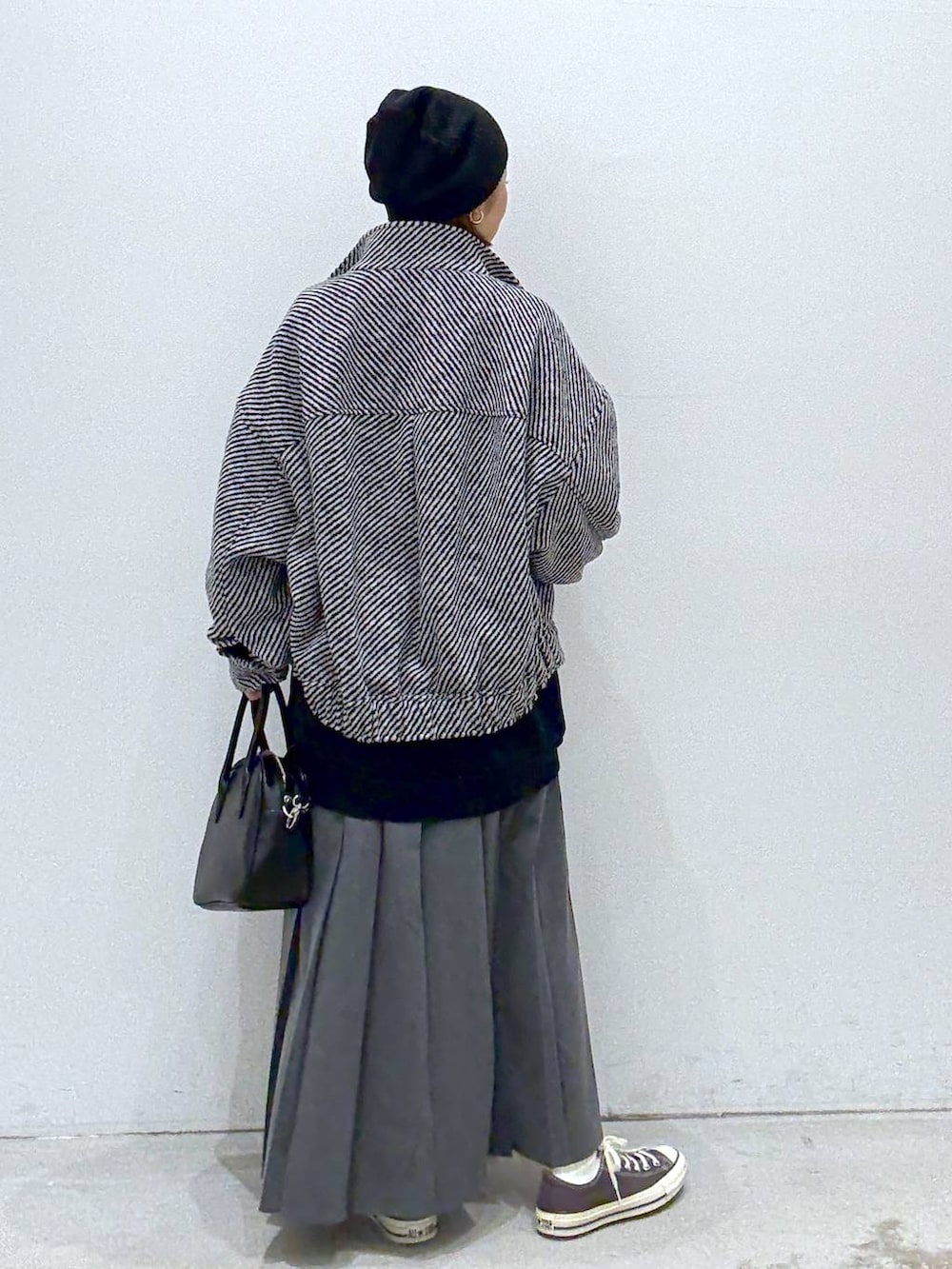 グレー系のスカート、ブラウン系のスニーカー、ブラック系のボストンバッグを着用したレディースの秋コーディネートの4枚目の写真