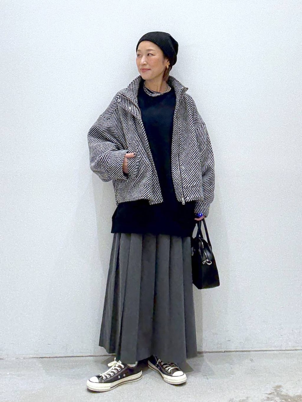 グレー系のスカート、ブラウン系のスニーカー、ブラック系のボストンバッグを着用したレディースの秋コーディネートの6枚目の写真