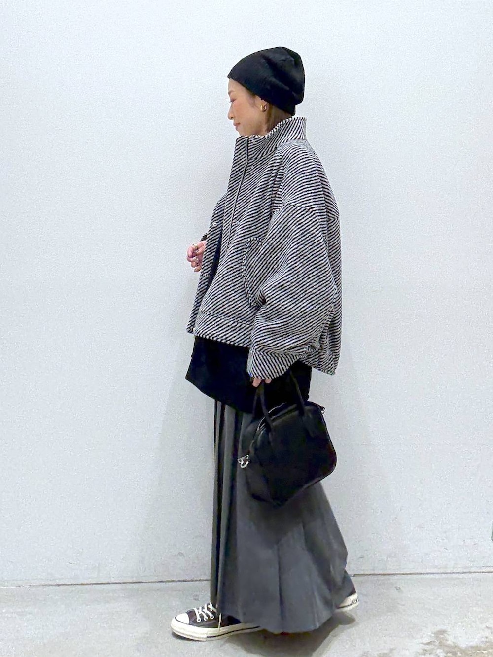 グレー系のスカート、ブラウン系のスニーカー、ブラック系のボストンバッグを着用したレディースの秋コーディネートの3枚目の写真