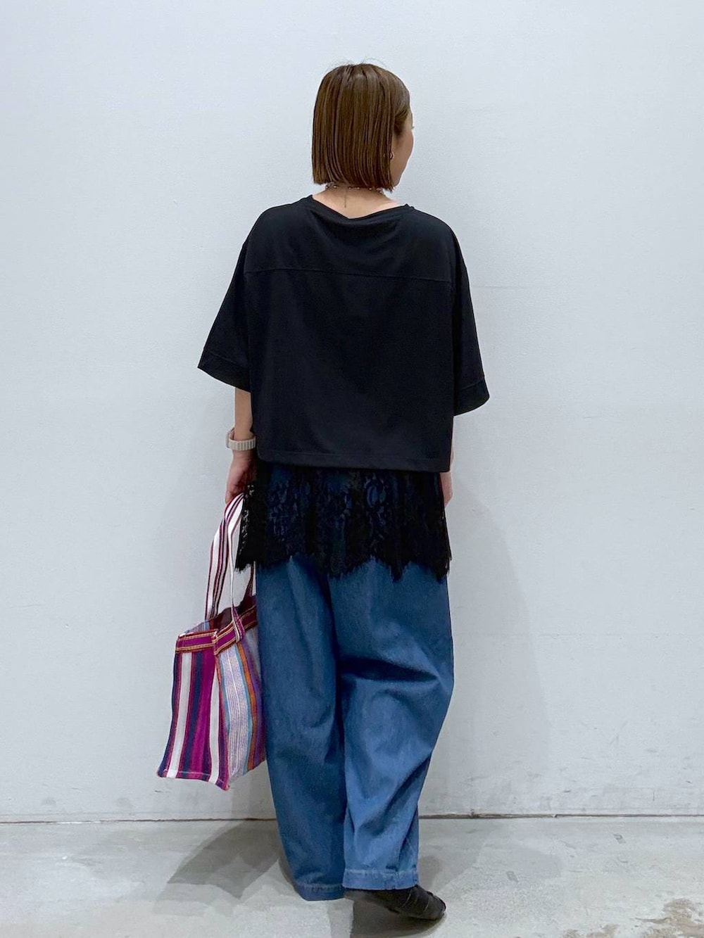 ブラック系のTシャツ/カットソー、ブラック系のパンプス、ブルー系のデニムパンツを着用したレディースの春コーディネートの4枚目の写真