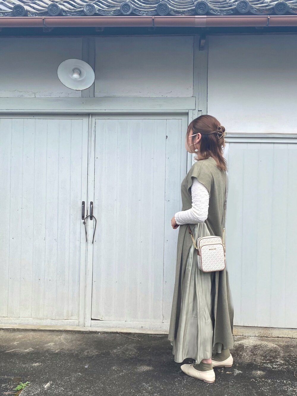 グリーン系のベスト、ホワイト系のTシャツ/カットソー、グリーン系のスカートを着用したレディースの春コーディネートの2枚目の写真