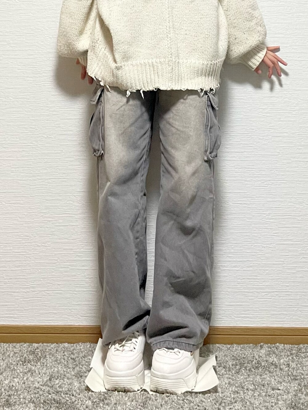 ホワイト系のニット/セーター、グレー系のデニムパンツ、ホワイト系のスニーカーを着用したレディースの秋コーディネートの4枚目の写真