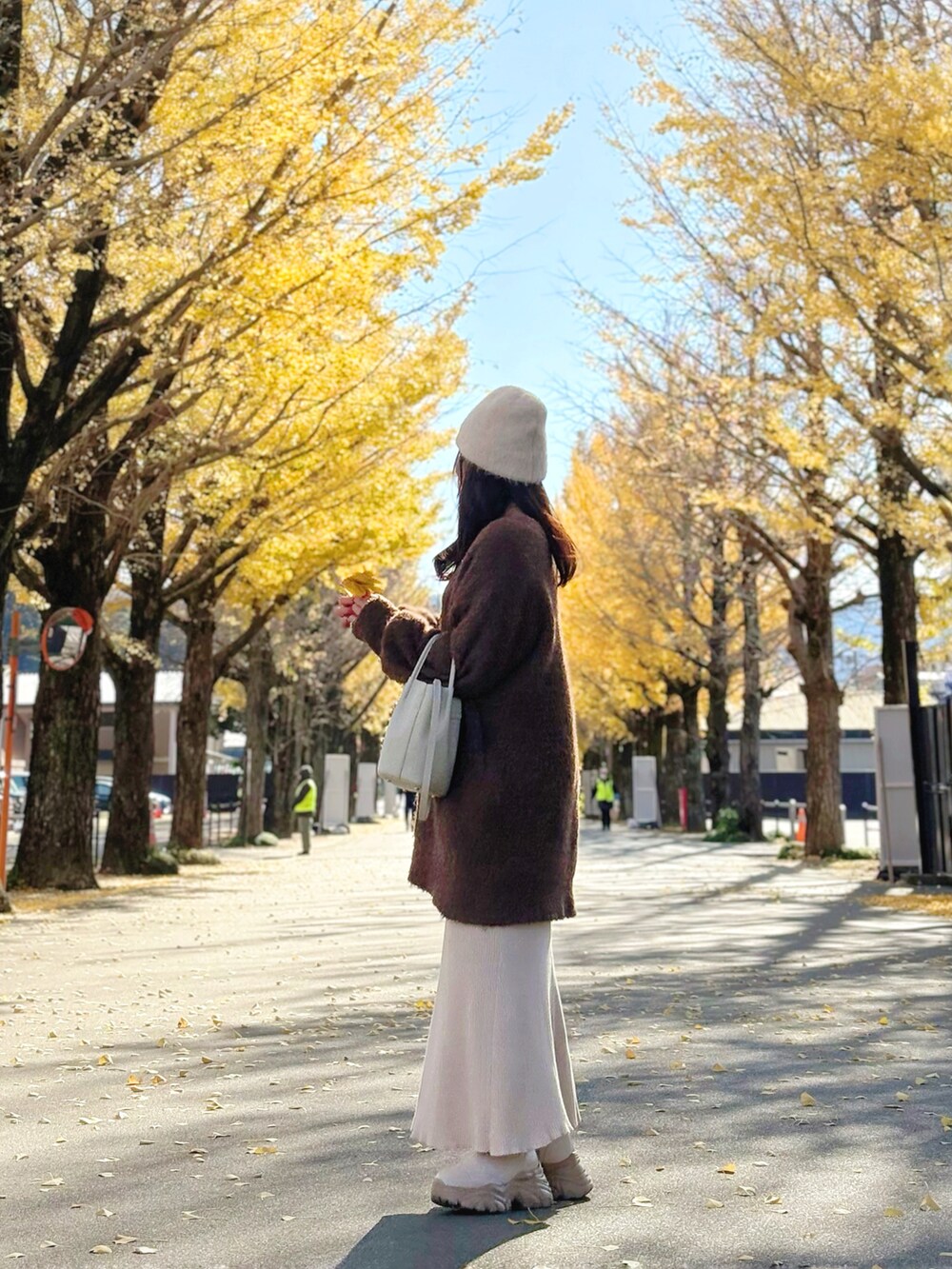 ブラウン系のチュニック、ホワイト系のショルダーバッグ、ベージュ系のスカートを着用したレディースの冬コーディネートの3枚目の写真