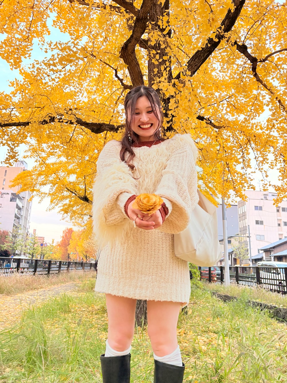 ベージュ系のニット/セーター、オレンジ系のTシャツ/カットソー、ブラック系のブーツを着用したレディースの秋コーディネートの2枚目の写真