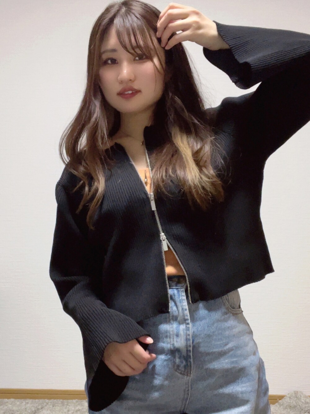 ブラック系のカーディガン/ボレロ、オレンジ系のキャミソール、ブルー系のデニムパンツを着用したレディースの秋コーディネートの3枚目の写真
