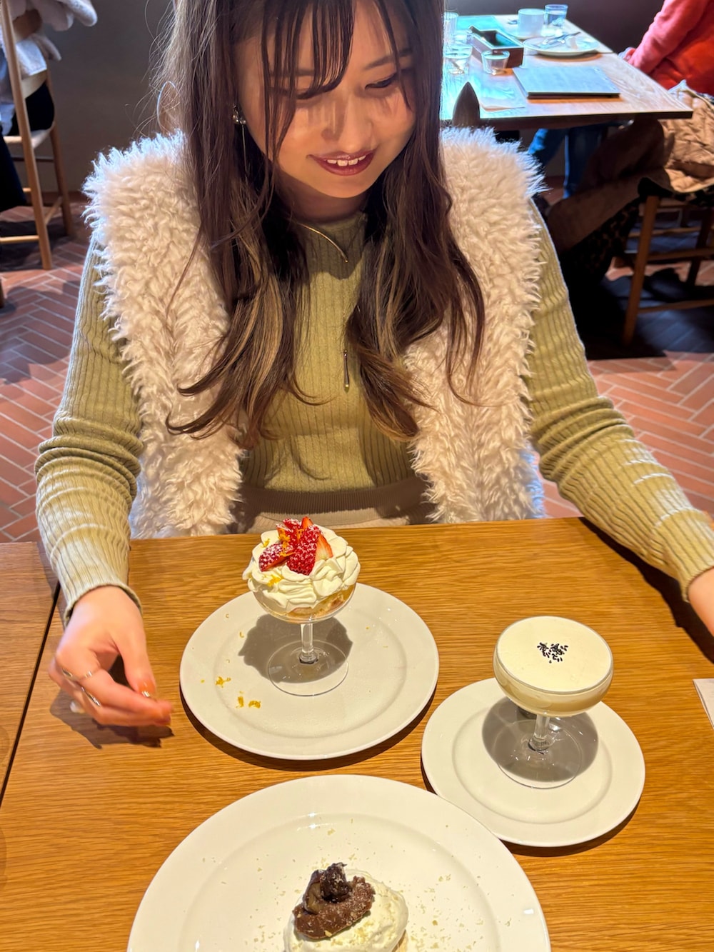 グリーン系のニット/セーター、ホワイト系のベスト、ベージュ系のスカートを着用したレディースの冬コーディネートの3枚目の写真