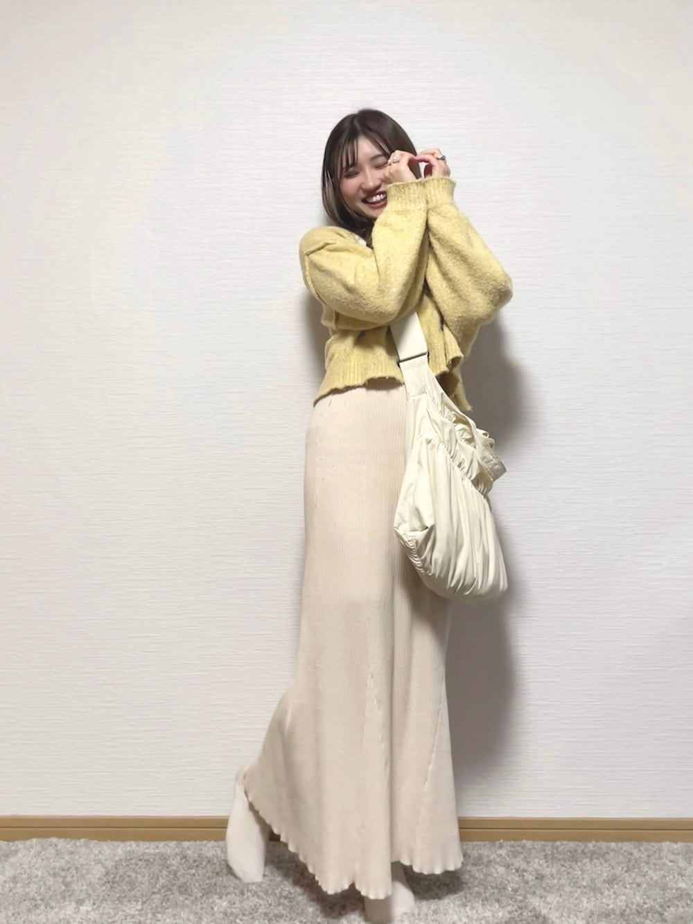 ベージュ系のタンクトップ、ホワイト系のショルダーバッグ、ベージュ系のスカートを着用したレディースの冬コーディネートの2枚目の写真