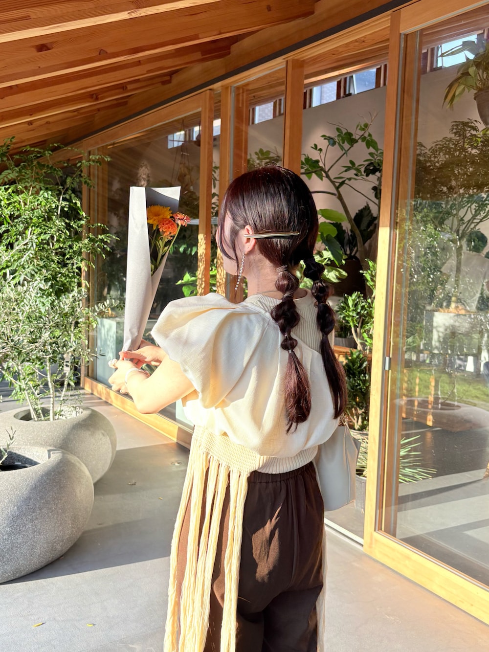 ブラウン系のパンツ、ベージュ系のチューブトップ、ホワイト系のニット/セーターを着用したレディースの夏コーディネートの5枚目の写真