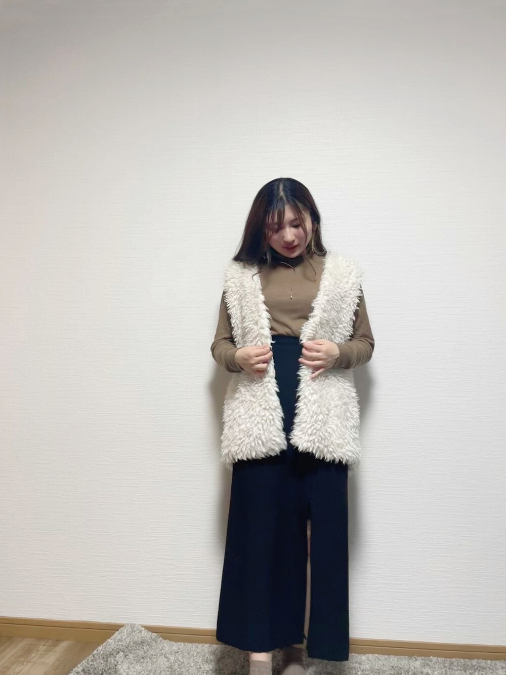 ホワイト系のベスト、ブラウン系のニット/セーター、ブラック系のスカートを着用したレディースの秋コーディネートの4枚目の写真