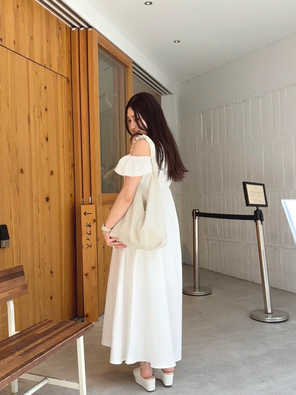 ホワイト系のワンピース、ホワイト系のトートバッグ、ゴールド系のネックレスを着用したレディースの夏コーディネートの2枚目の写真