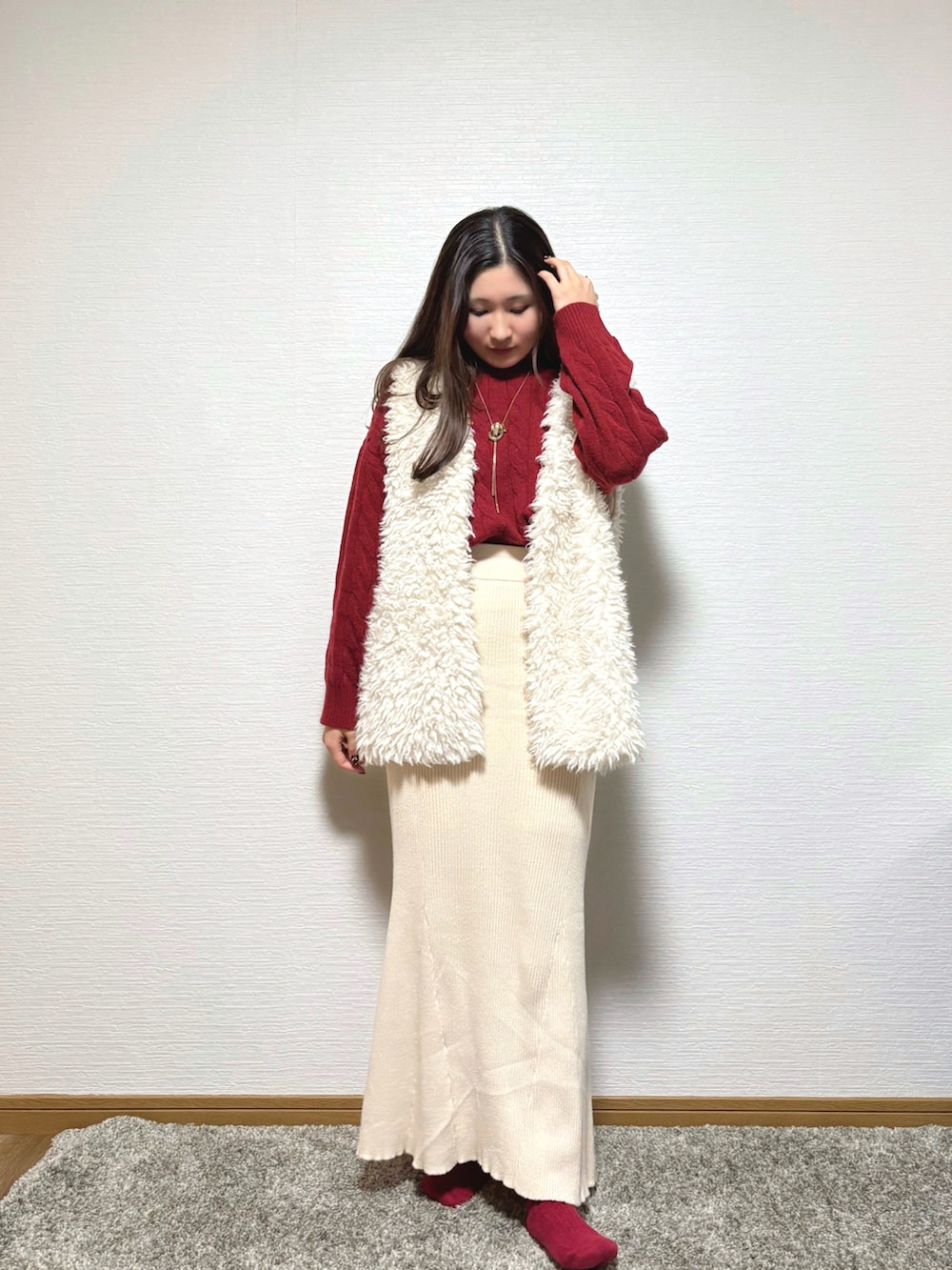 ホワイト系のベスト、ベージュ系のスカートを着用したレディースの冬コーディネートの2枚目の写真