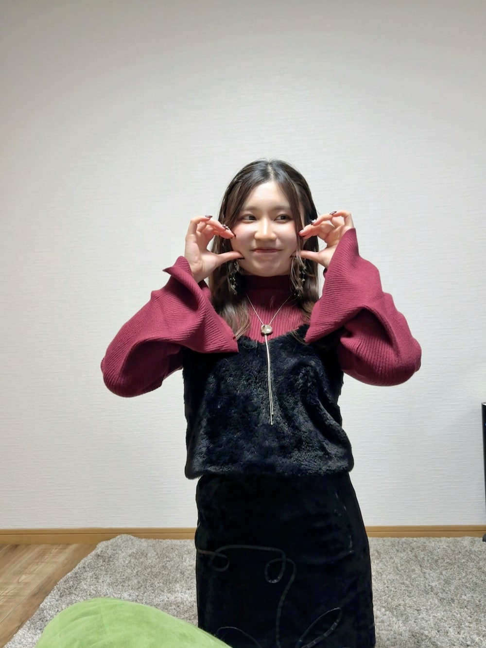 レッド系のニット/セーター、ブラック系のスカート、ホワイト系のスリッポンを着用したレディースの冬コーディネートの3枚目の写真