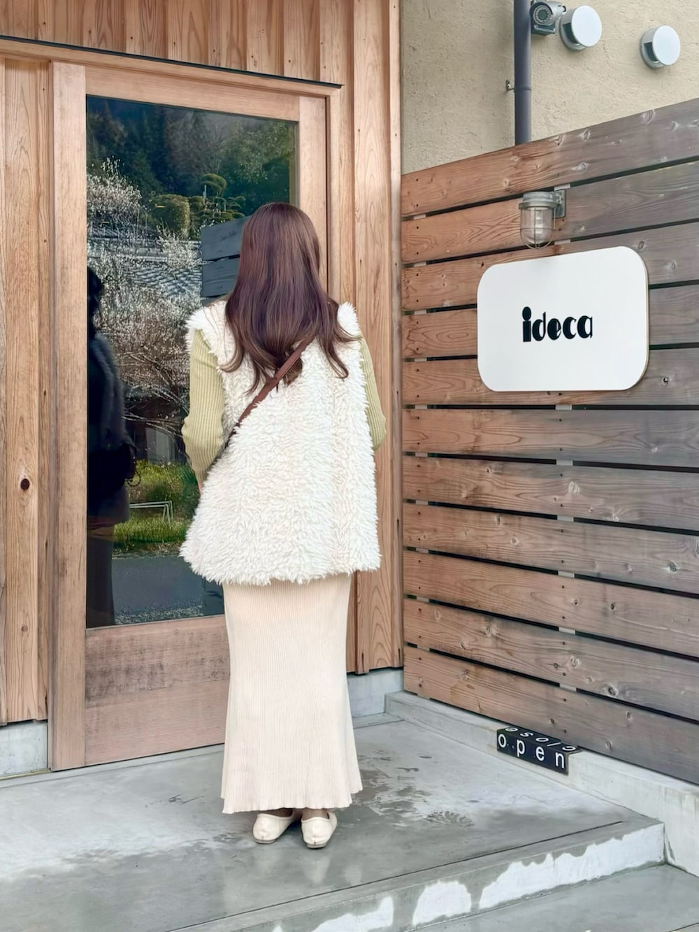 グリーン系のニット/セーター、ホワイト系のベスト、ベージュ系のスカートを着用したレディースの冬コーディネートの2枚目の写真