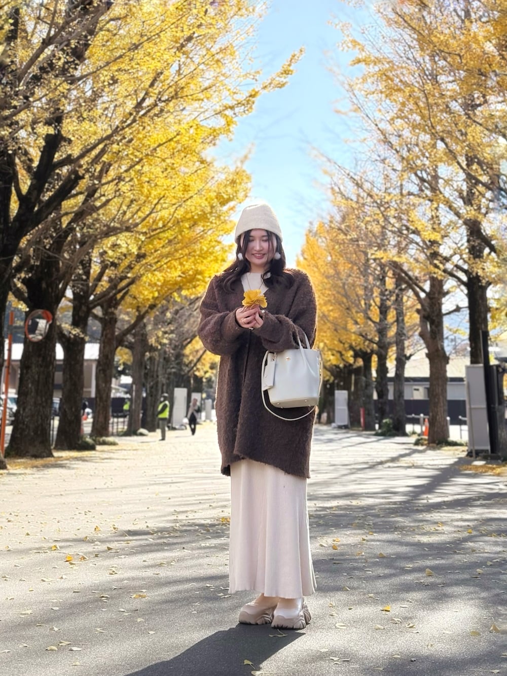 ブラウン系のチュニック、ホワイト系のショルダーバッグ、ベージュ系のスカートを着用したレディースの冬コーディネートの2枚目の写真