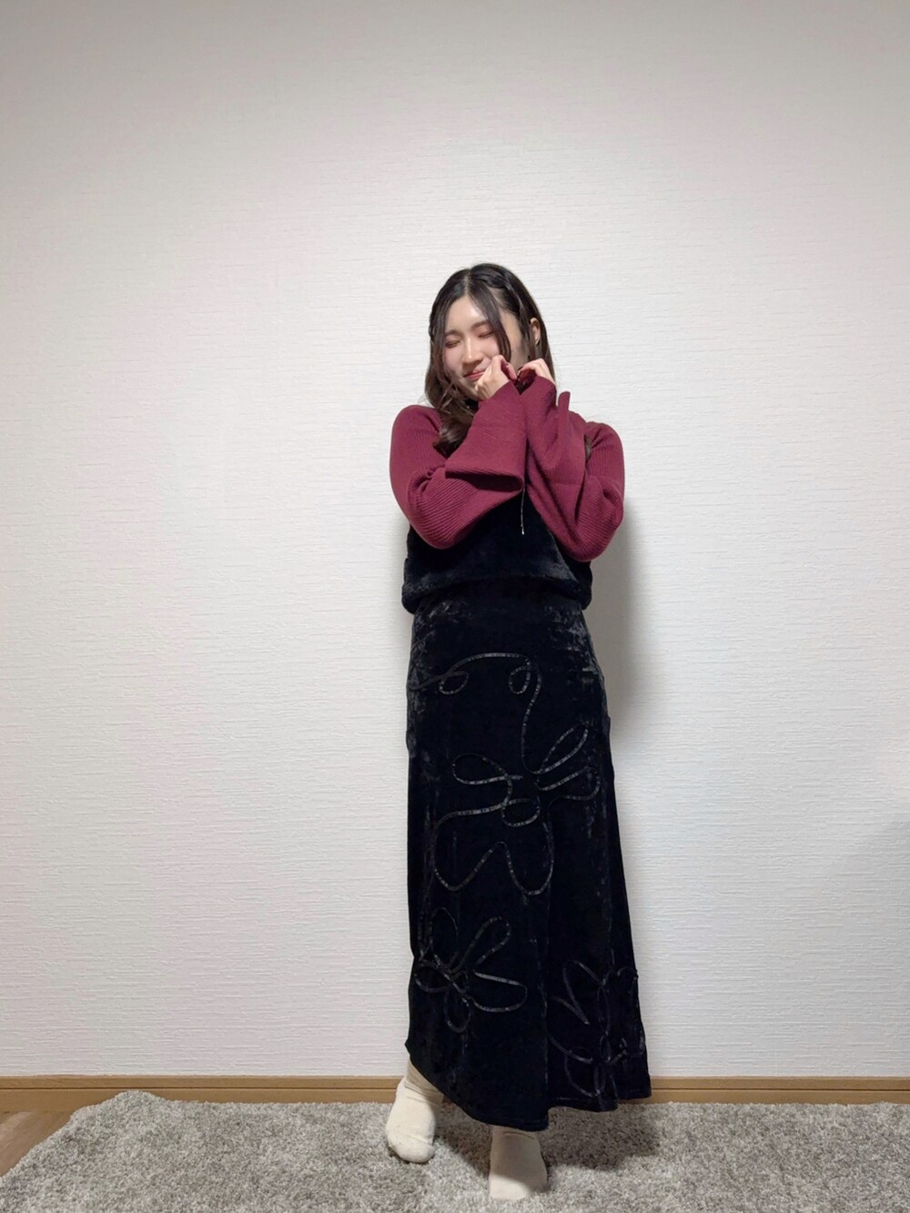 レッド系のニット/セーター、ブラック系のスカート、ホワイト系のスリッポンを着用したレディースの冬コーディネートの2枚目の写真