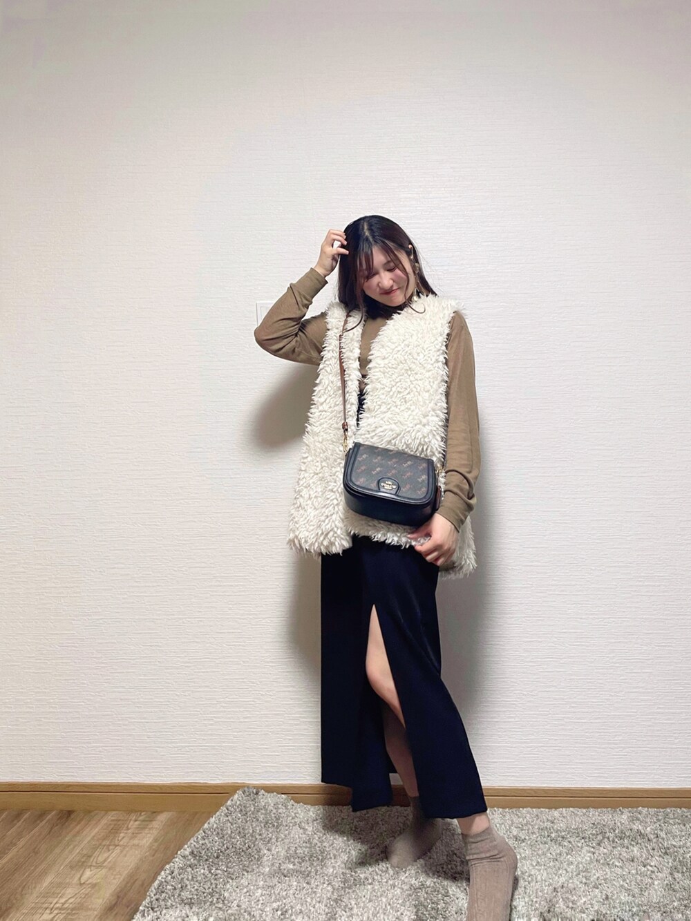 ホワイト系のベスト、ブラウン系のニット/セーター、ブラック系のスカートを着用したレディースの秋コーディネートの2枚目の写真