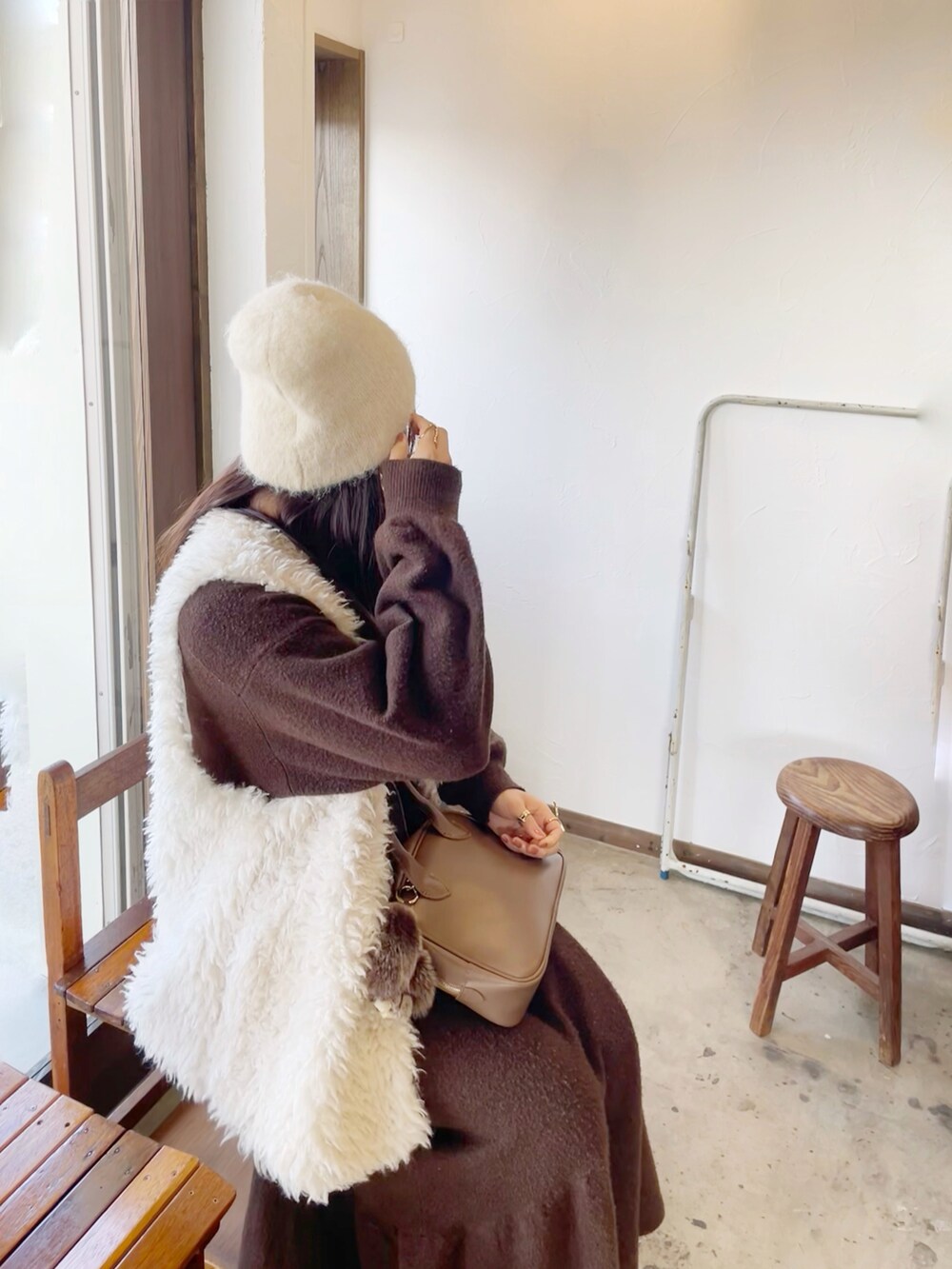 ブラウン系のワンピース、ホワイト系のベスト、ベージュ系のショルダーバッグを着用したレディースの冬コーディネートの2枚目の写真