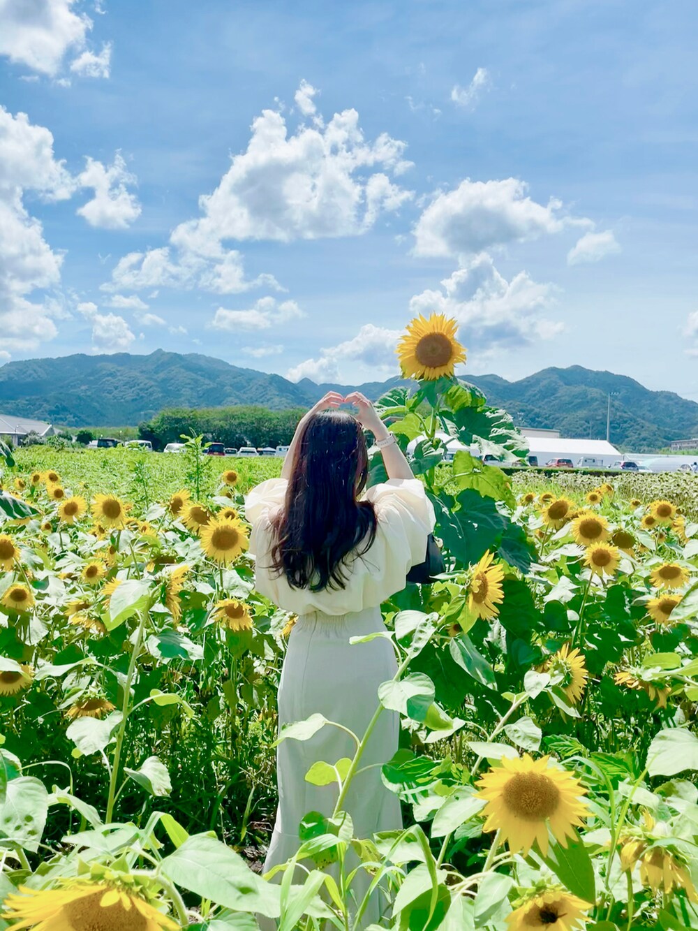 ベージュ系のシャツ/ブラウス、ホワイト系のスカート、ゴールド系のチョーカーを着用したレディースの夏コーディネートの2枚目の写真