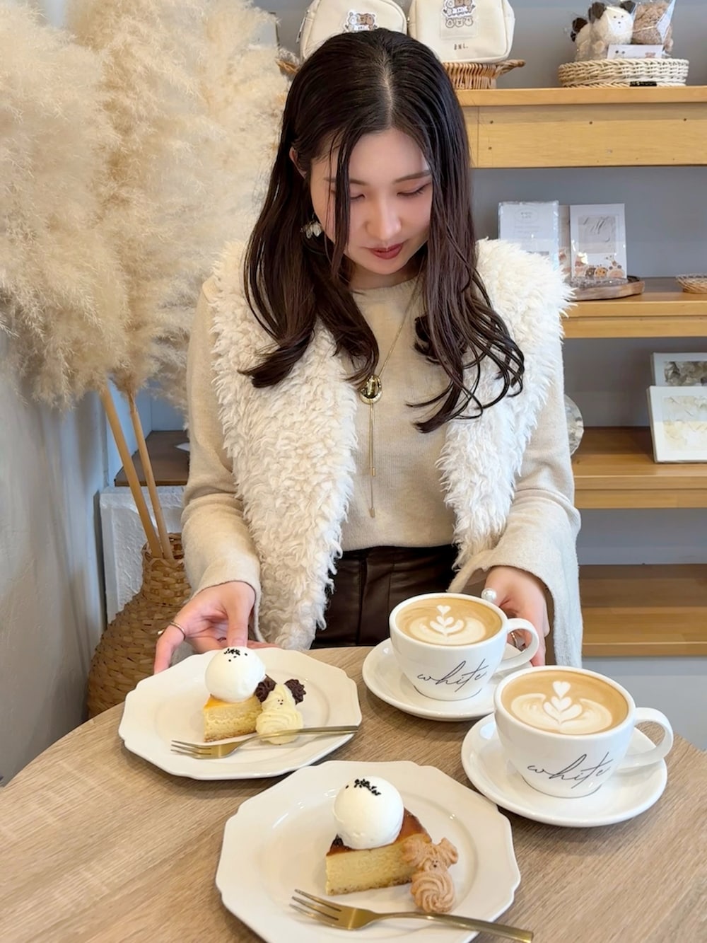 ホワイト系のニット/セーター、ホワイト系のベスト、ブラック系のブーツを着用したレディースの秋コーディネートの3枚目の写真