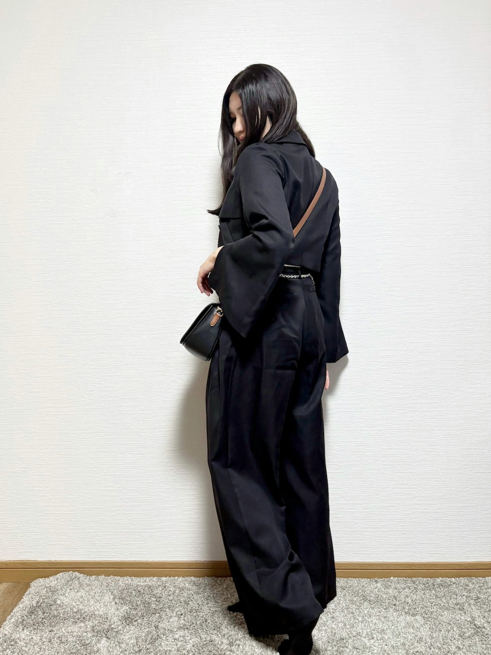 グレー系のテーラードジャケット、ブラック系のスラックス、ベージュ系のキャミソールを着用したレディースの秋コーディネートの3枚目の写真