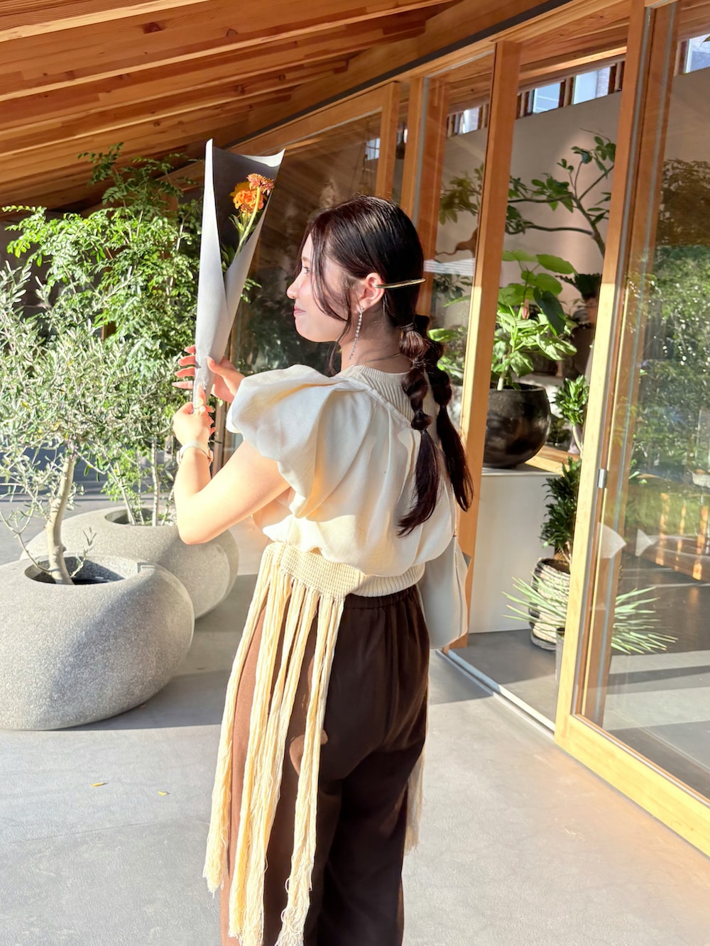 ブラウン系のパンツ、ベージュ系のチューブトップ、ホワイト系のニット/セーターを着用したレディースの夏コーディネートの3枚目の写真