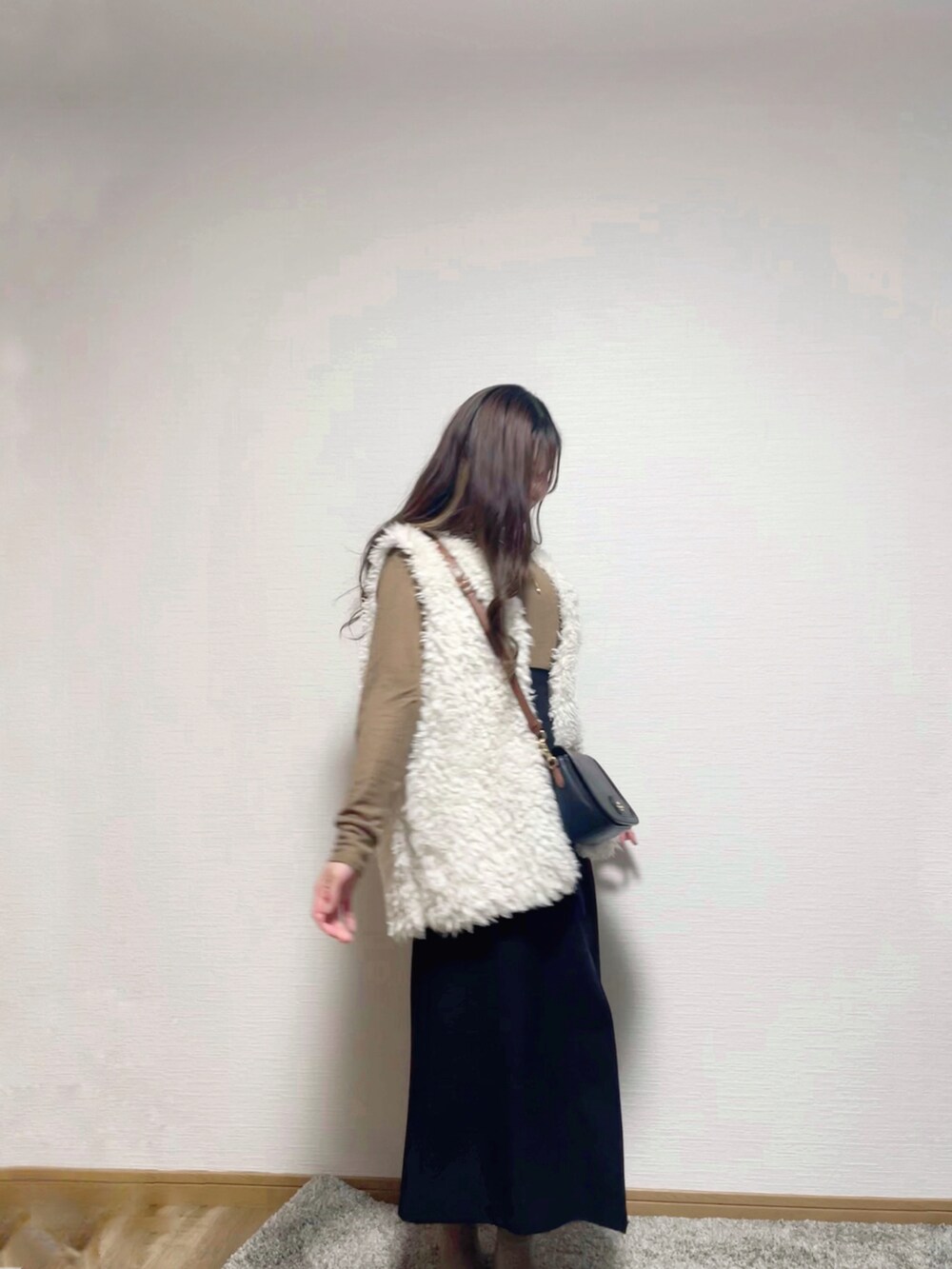 ホワイト系のベスト、ブラウン系のニット/セーター、ブラック系のスカートを着用したレディースの秋コーディネートの3枚目の写真