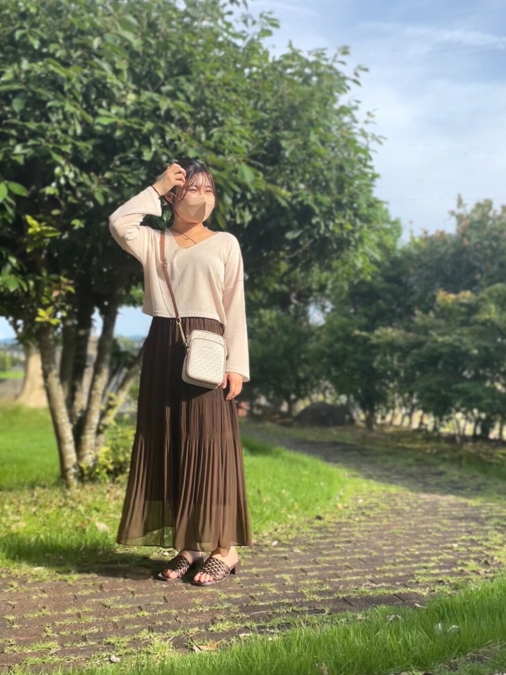 ブラウン系のスカート、ベージュ系のトップス、ブラウン系のキャミソールを着用したレディースの夏コーディネートの2枚目の写真