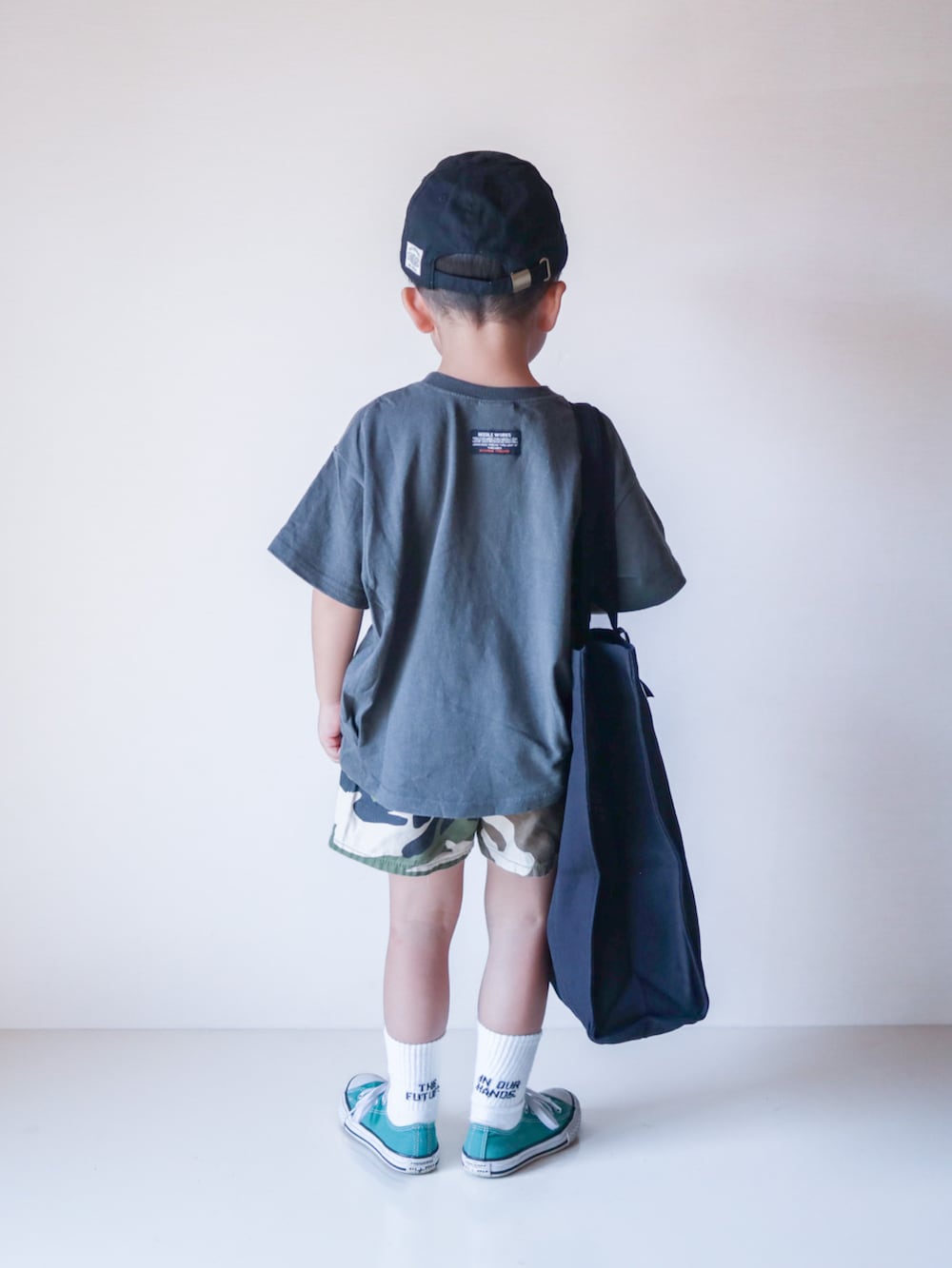 グレー系のTシャツ/カットソー、ブラック系のトートバッグ、グリーン系のスニーカーを着用したキッズの夏コーディネートの3枚目の写真