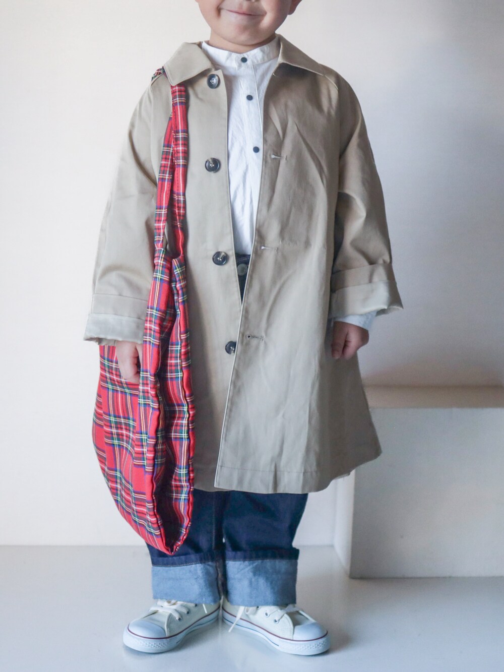 ベージュ系のステンカラーコート、ホワイト系のシャツ/ブラウス、ブルー系のデニムパンツを着用したキッズの春コーディネートの4枚目の写真