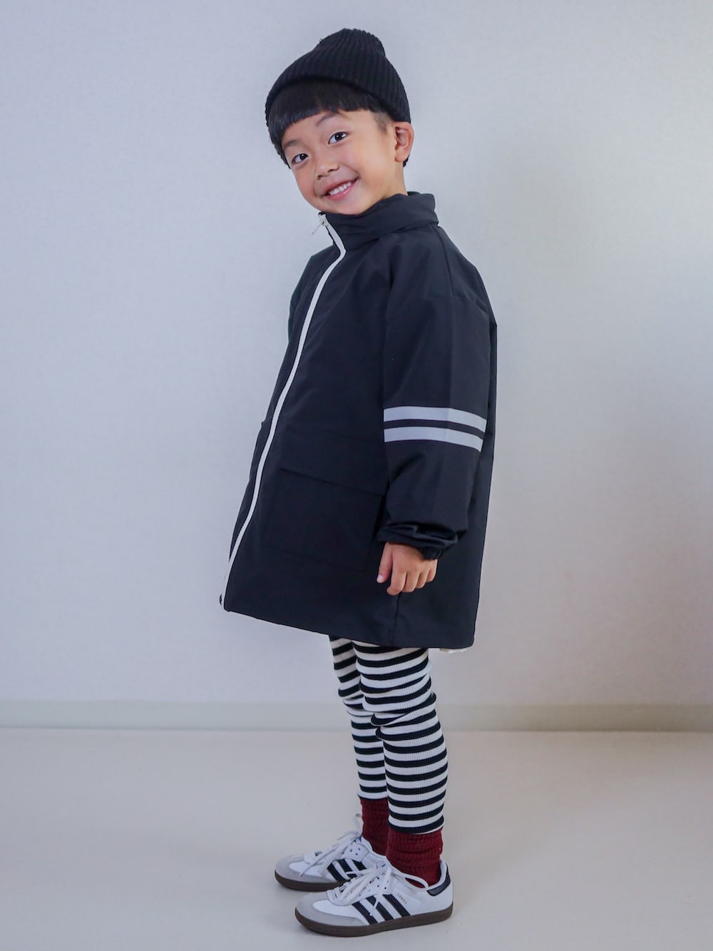 ブラック系のナイロンジャケット、ホワイト系のスニーカー、レッド系のキャップを着用したキッズの秋コーディネートの3枚目の写真