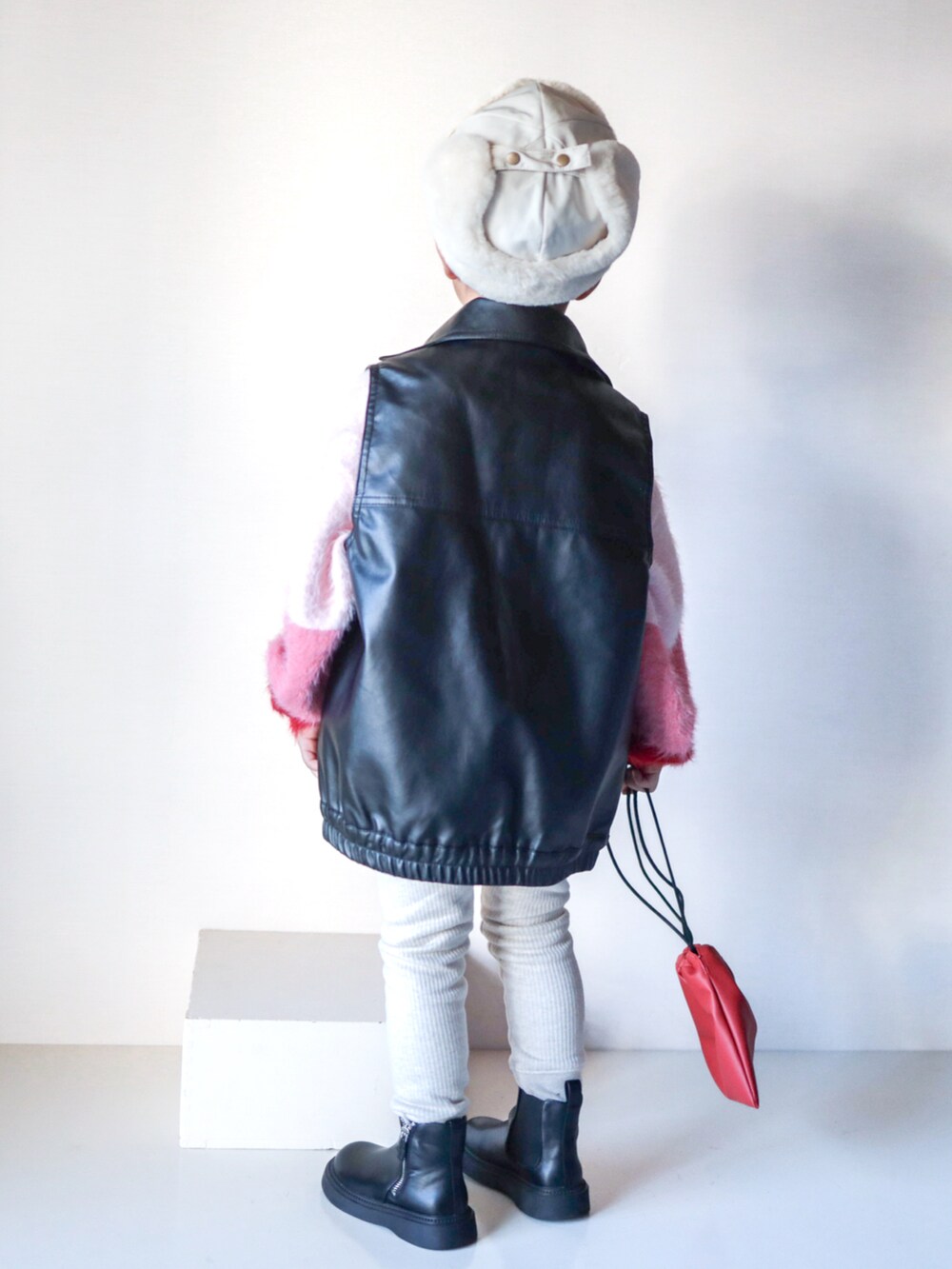 ピンク系のニット/セーター、ブラック系のジャケット/アウター、ブラック系のブーツを着用したキッズの秋コーディネートの3枚目の写真