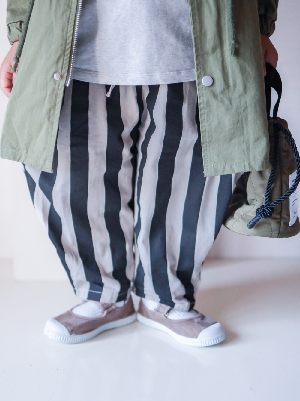 ブラック系のその他パンツ、ホワイト系のTシャツ/カットソー、グリーン系のショルダーバッグを着用したキッズの春コーディネートの3枚目の写真