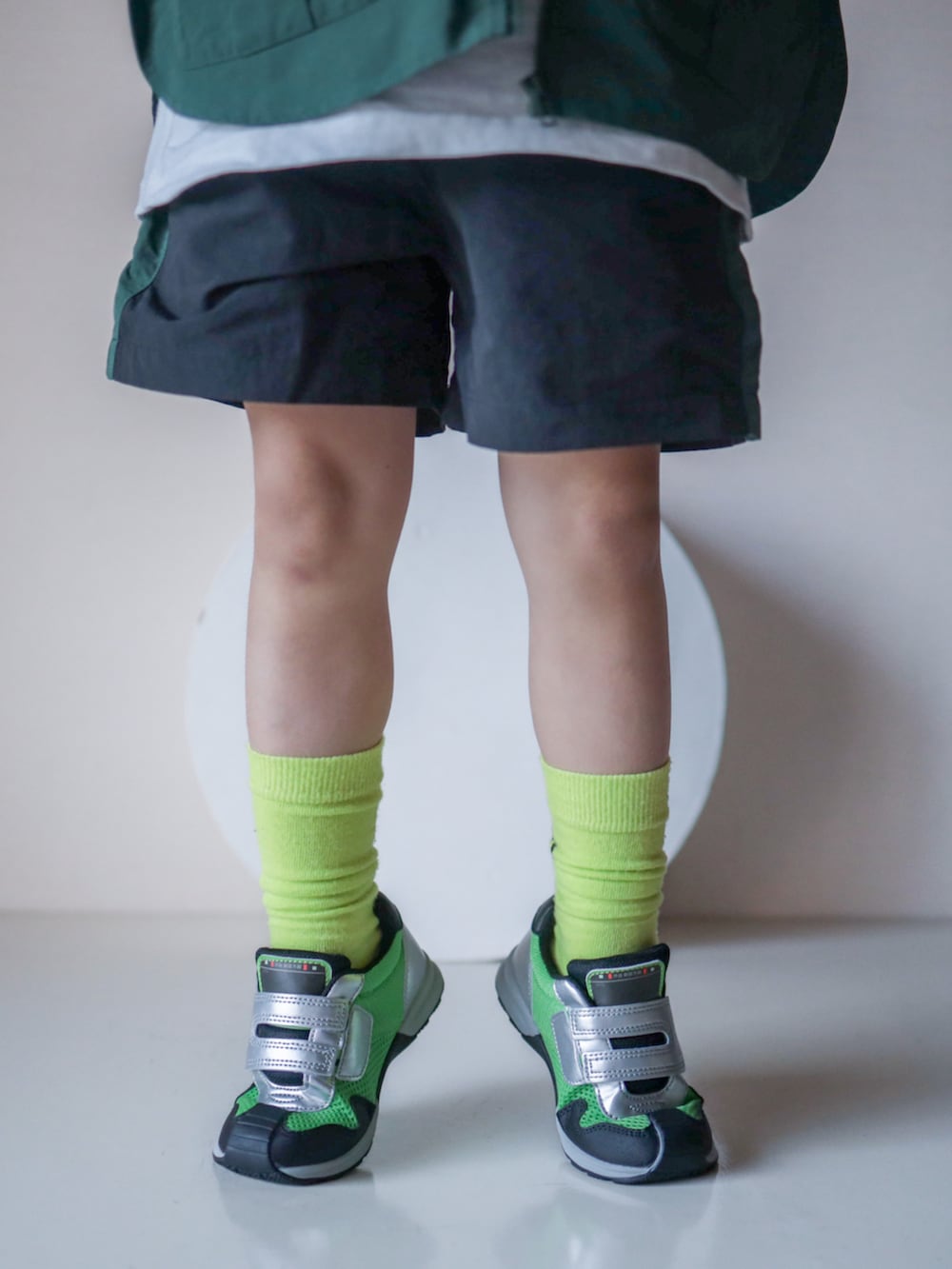 グリーン系のベスト、ブラック系のその他パンツ、グリーン系のシューズを着用したキッズの春コーディネートの2枚目の写真