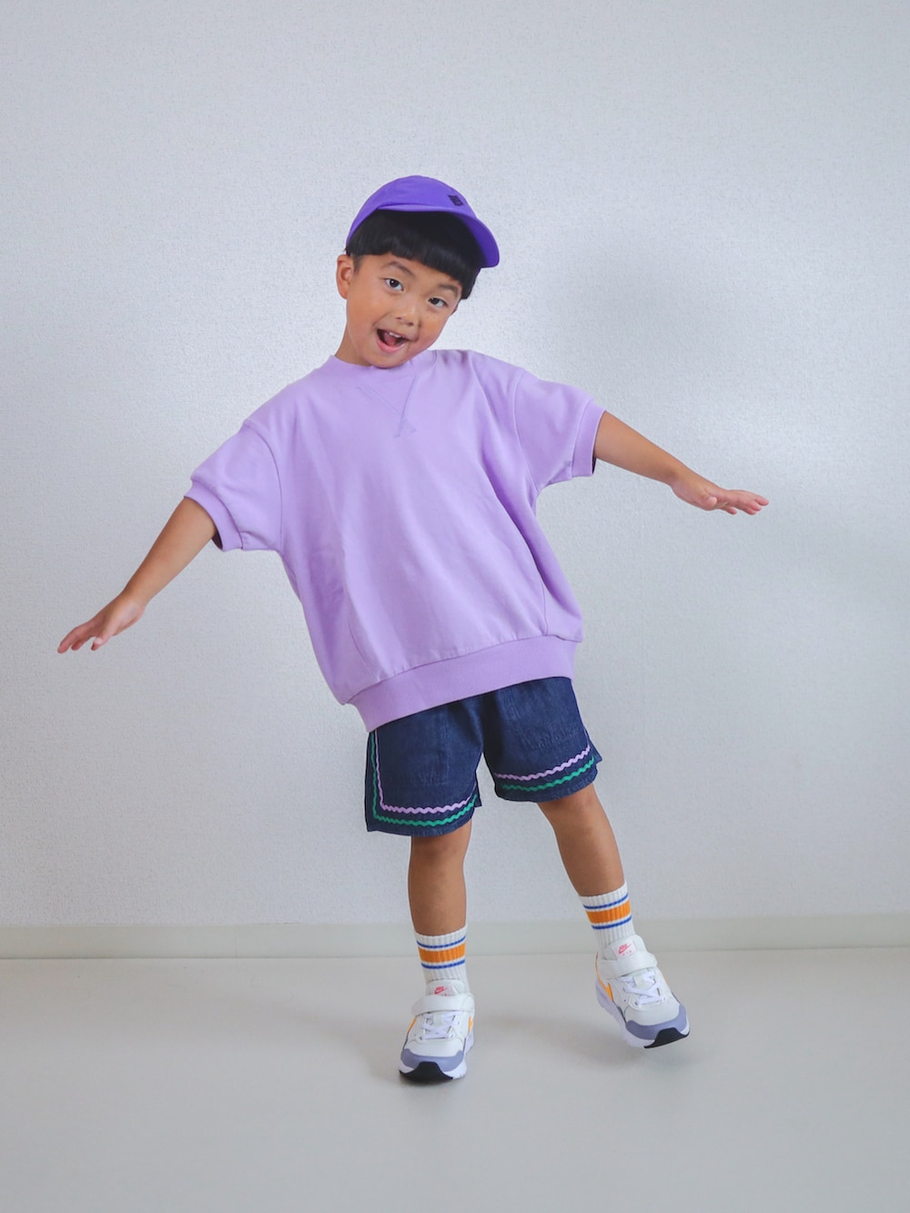 パープル系のTシャツ/カットソー、ブルー系のデニムパンツ、ホワイト系のスニーカーを着用したキッズの夏コーディネートの2枚目の写真