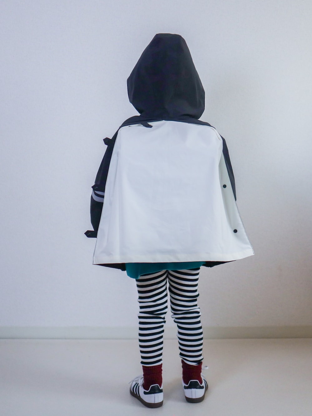 ブラック系のナイロンジャケット、ホワイト系のスニーカー、レッド系のキャップを着用したキッズの秋コーディネートの5枚目の写真