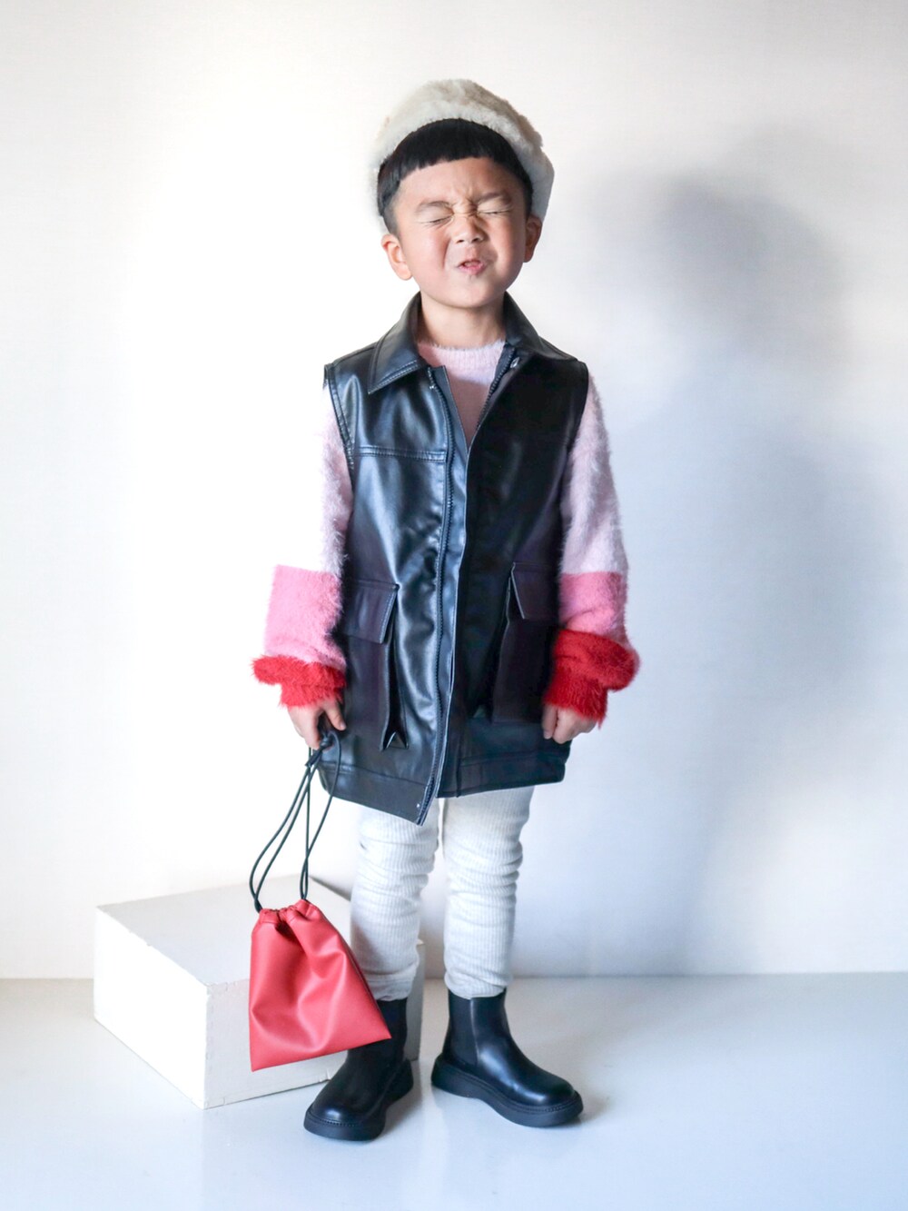 ピンク系のニット/セーター、ブラック系のジャケット/アウター、ブラック系のブーツを着用したキッズの秋コーディネートの4枚目の写真