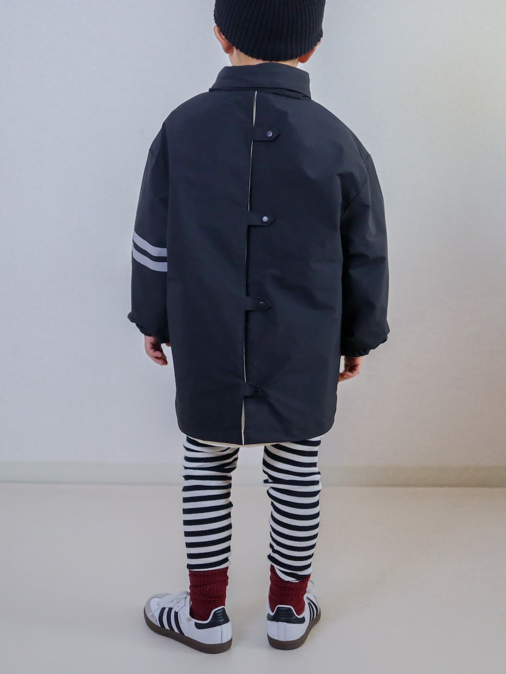 ブラック系のナイロンジャケット、ホワイト系のスニーカー、レッド系のキャップを着用したキッズの秋コーディネートの4枚目の写真